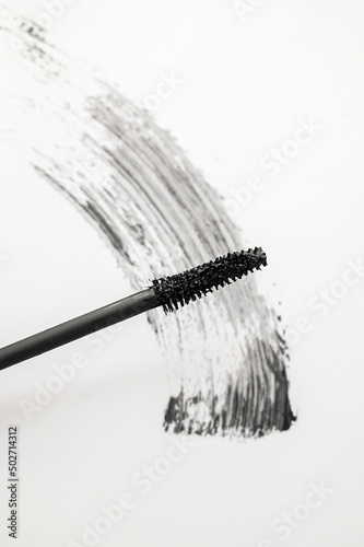 Black mascara with brush applicator close-up, isolated on white background. Beauty product.