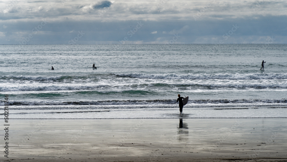 Surfers and stand up paddle boarders at Sumner Beach, Aotearoa / New Zealand.