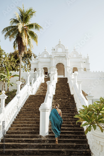 A girl in a sari walks the steps in a white Buddhist temple in Sri Lanka