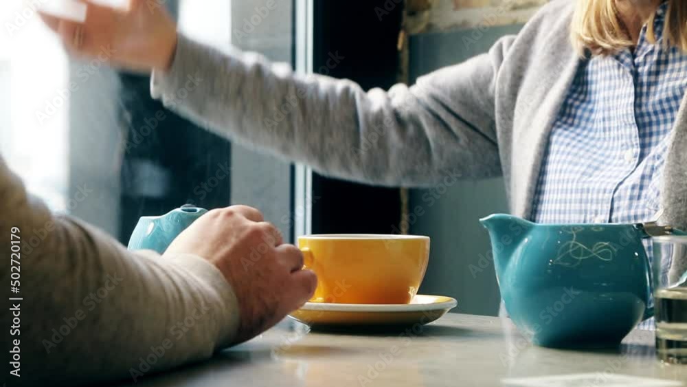 A conversation between a man and a woman over a cup of coffee. The woman is gesturing. Yellow cup and blue coffee pot. No faces, only hands A conversation between a man and a woman over a cup of coffee. The woman is gesturing. Yellow cup and blue coffee pot. No faces, only hands