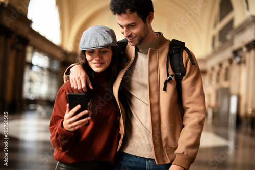 Beautiful couple at railway station waiting for the train. Young woman and man waiting to board a train © JustLife