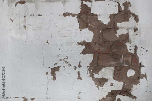 .texture of an old wall with crumbling plaster and a brick under it