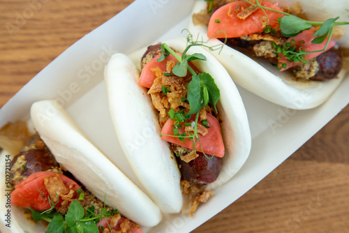 Boa bun with sausage pickles and micro greens out of focus with grain