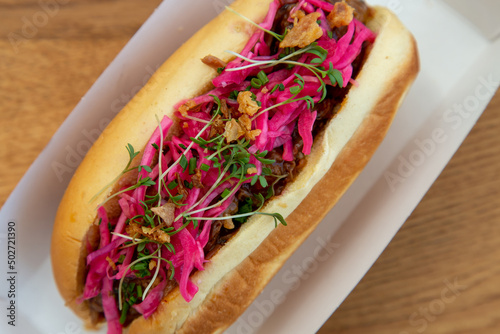 pulled beef on roll with pink pickled onion low light with grain and out of focus photo