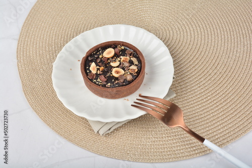 luxury home baked rocher dark rich chocolate tart in 3 layer with hazelnut mixed nuts and gold foil in white background halal dessert menu for hotel cafe photo