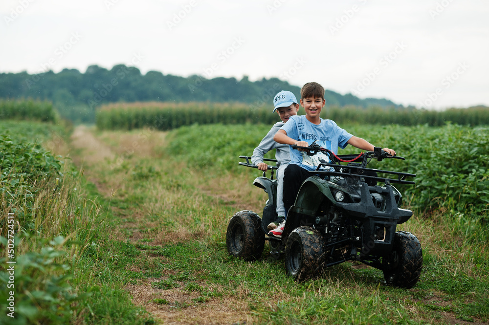 Two brothers driving four-wheller ATV quad bike. Happy children moments. Two brothers driving four-wheller ATV quad bike. Happy children moments.