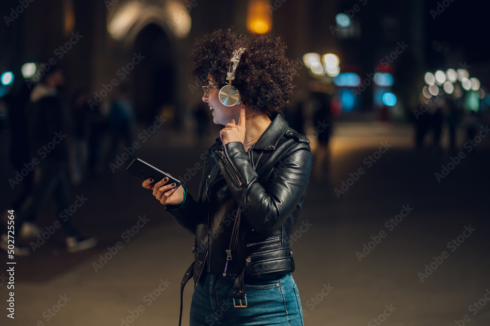 Woman walking in the city streets and using smartphone and headphones