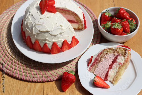 Cut Zuccotto, traditional italian dome shaped cake with white chocolate  and strawberries cream on wooden table. Charlotte cake with strawberries photo