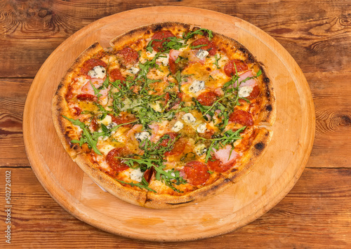 Pizza with meat products on the round wooden pizza board