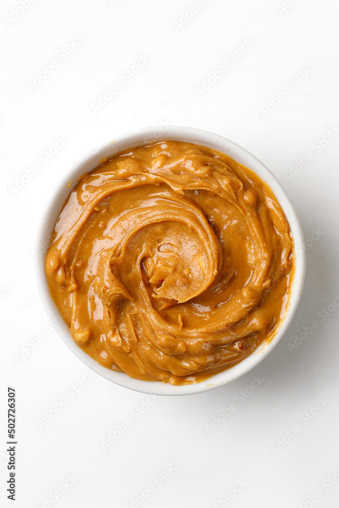 Peanut butter in a white saucer on white background. Curl of Peanut butter. Top view.