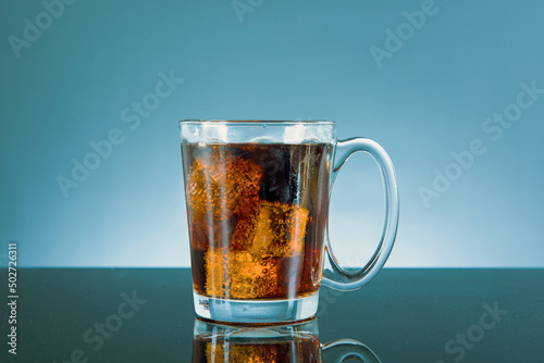 cola with ice in a glass bottle on blue background.