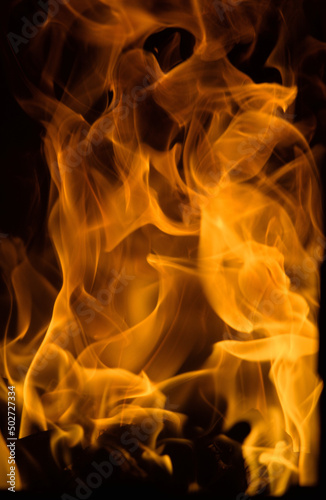 Flame. Orange flames on a dark background. The texture is a raging fire of bright orange color on a dark background.