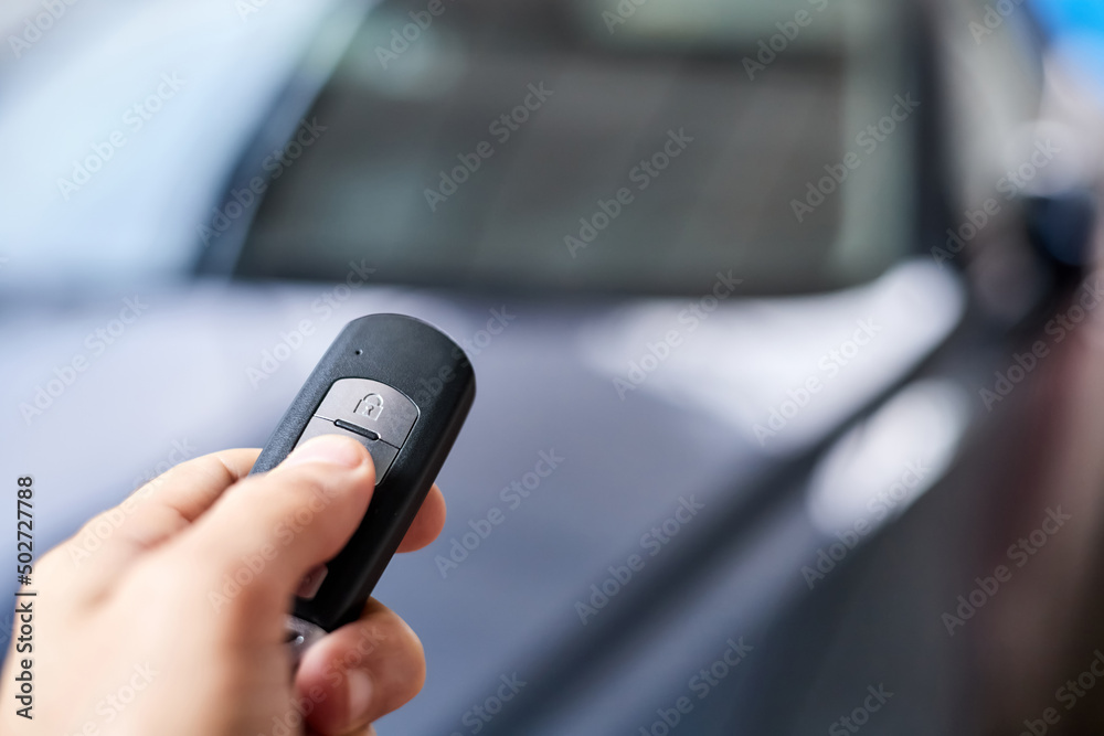 The car owner holds in his hand a remote control device for keyless entry. Close-up, selective focus