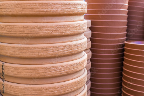 There are many large cone-shaped ceramic pots for plants. Brown clay flower pots in stacks.