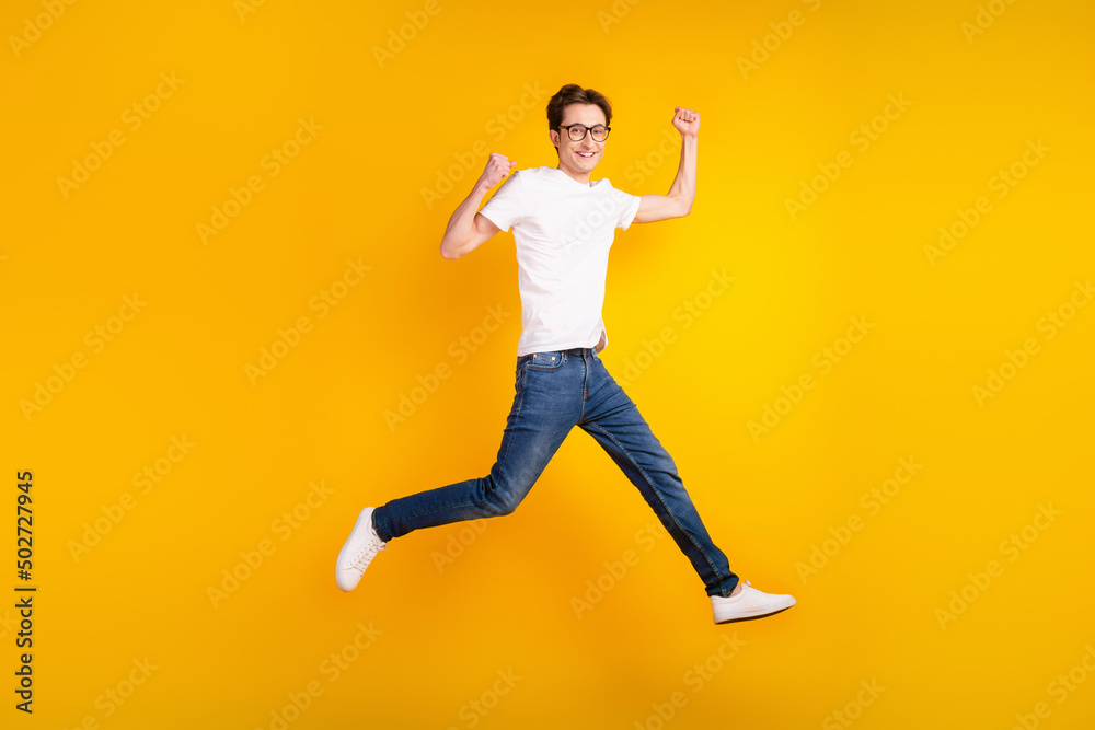 Full body photo of young man jump up run rejoice winner fists hands triumph isolated over yellow color background