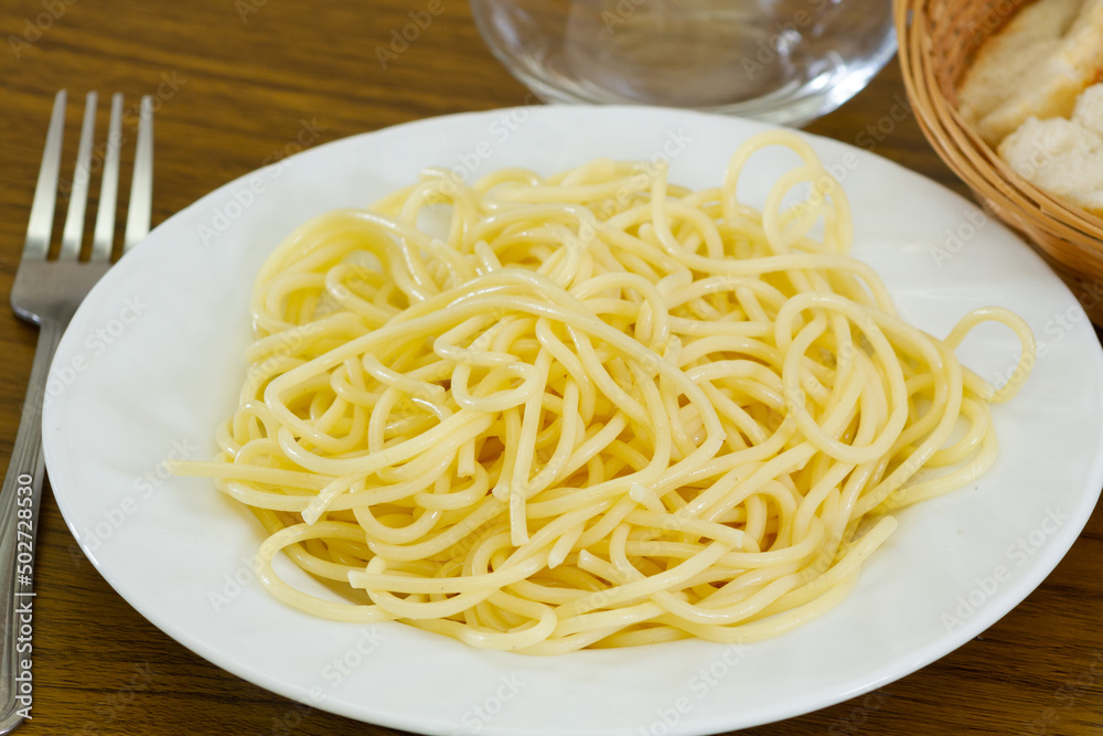 dish of plain cooked spaghetti on a table dish of plain cooked spaghetti on a table