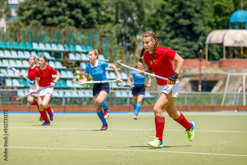 Young women field hockey players running on the pitch during the game