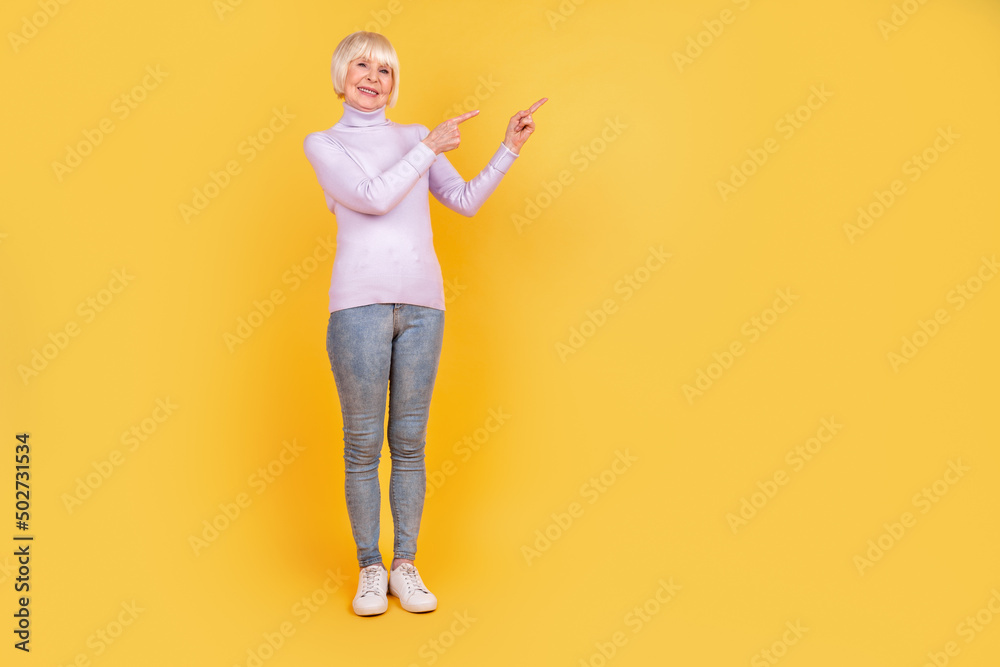 Full body photo of senior lady indicate fingers empty space ad choice promo isolated over yellow color background Full body photo of senior lady indicate fingers empty space ad choice promo isolated over yellow color background