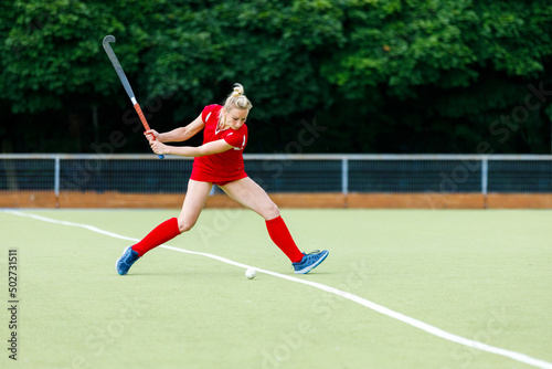 Young woman field hockey player hit the ball in attack on game. © skumer