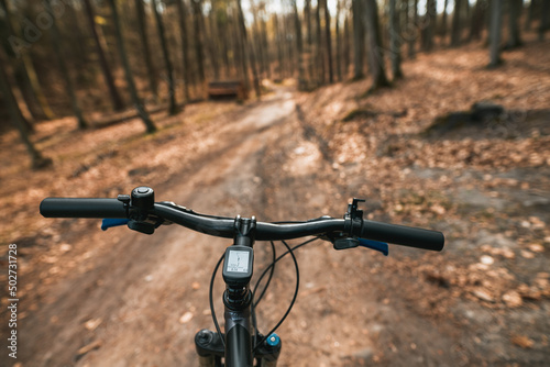 Top view of mountain bike handlebar and blurred cross country forest road. Concept of extreme activity on the woods trails. © AlexGo