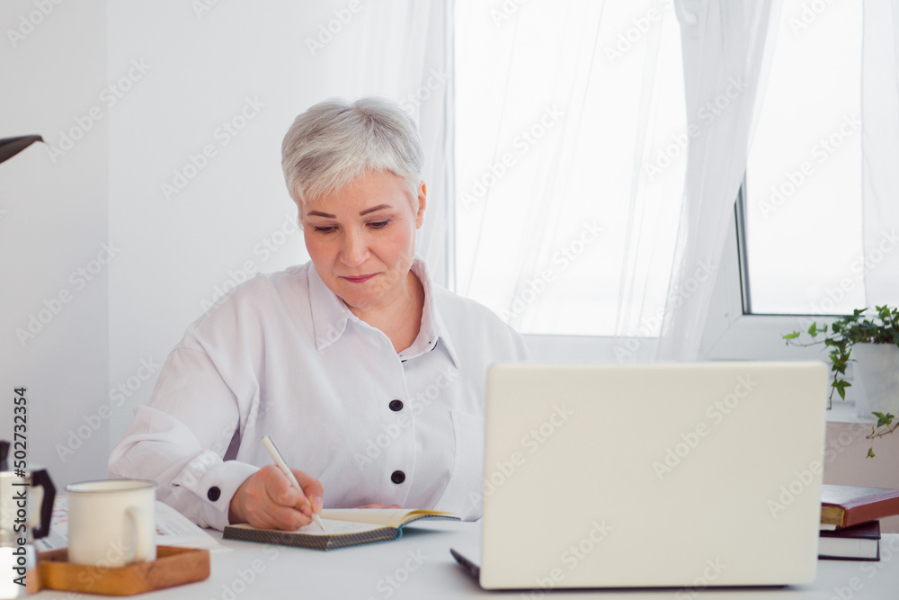 gray-haired businesswoman working at a desk with a computer gray-haired businesswoman working at a desk with a computer