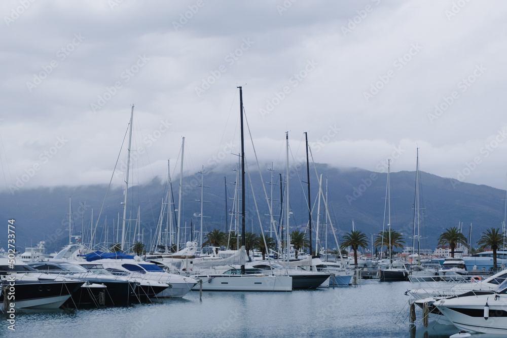 yachts in marina on a cloudy sky day over mountains landscape. luxury transport in a port. sailing boats in calm adriatic sea, Porto Montenegro