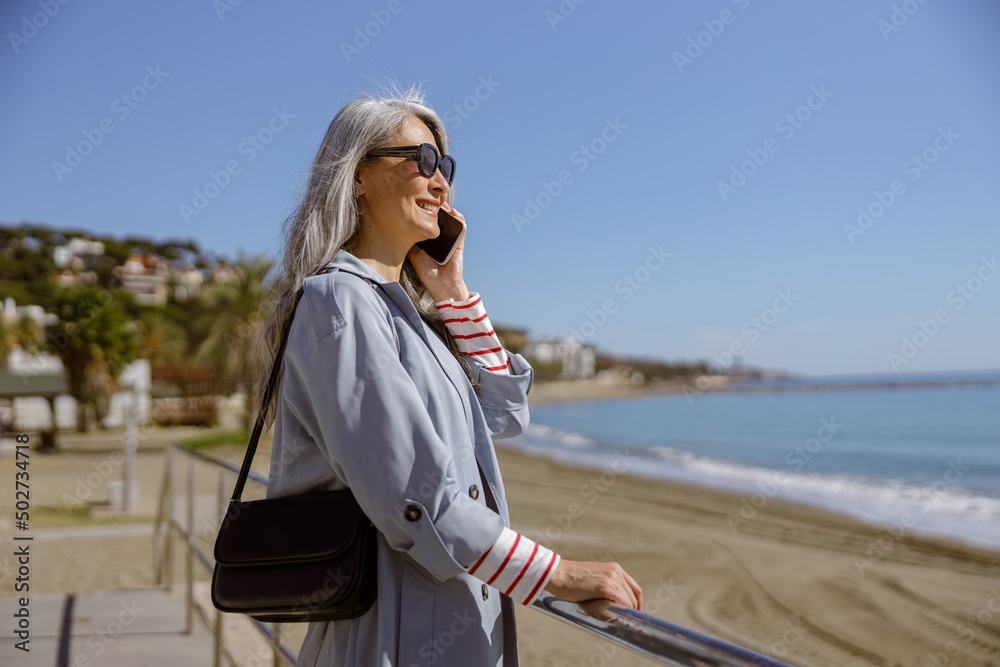 Cheerful mature lady relaxing outdoors at coastline Cheerful mature lady relaxing outdoors at coastline