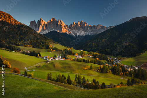 Autumn sunset in Val di Funes in the Italian Dolomites. Fall colors create beautiful contrasts with the blue sky.