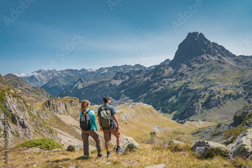 Young Attractive Couple looking the panoramic views of the amazing mountains landscape in summer. Discovery Travel Destination and Freedom Concept. © deliris