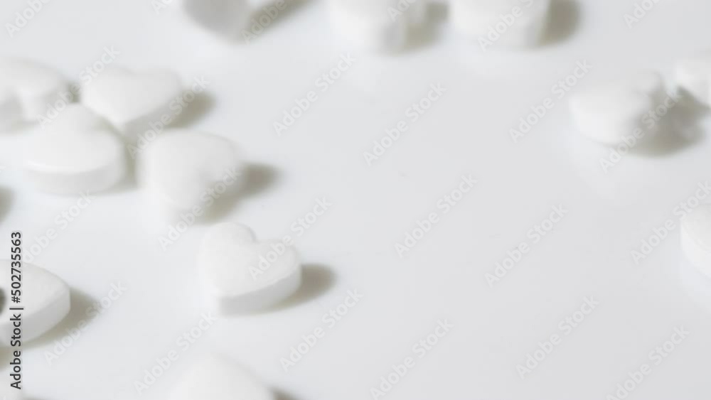 Macro white heart shape drugs, closeup medical pills falling, medicine concept Macro white heart shape drugs, closeup medical pills falling, medicine concept