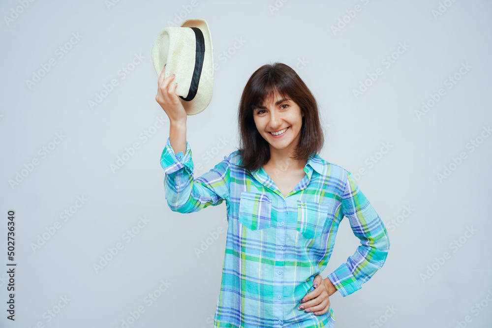 Young smiling brunet caucasian woman taking off hat isolated on gray background Young smiling brunet caucasian woman taking off hat isolated on gray background