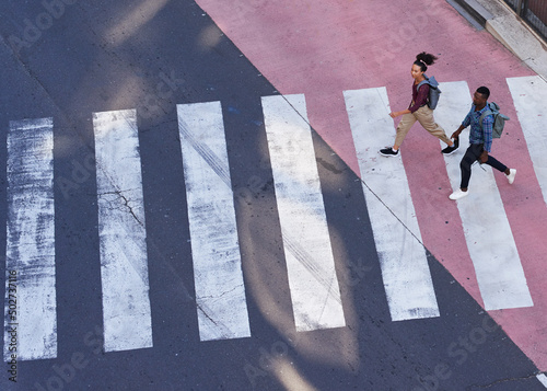 Two young pedestrians cross the road on a crosswalk in the city photo