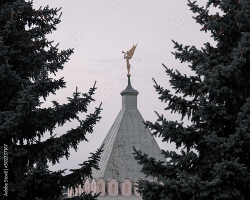 View of Angel on the top of Gate tower of Optina Pustyn monastery on cloudy summer day. Kaluga Oblast, Russia. photo