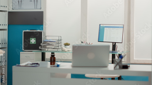 Nobody in medical office with modern technology and tools used for health care service consultation. No people in empty cabinet with medical equipment, laptop and checkup instruments.