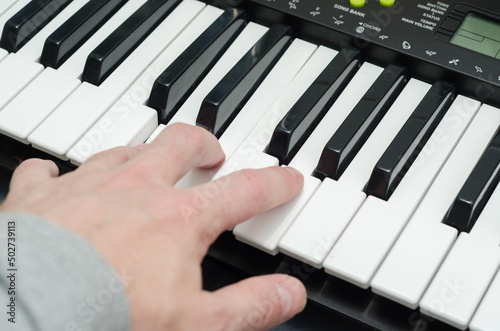 man s hand on the keys of a synthesizer