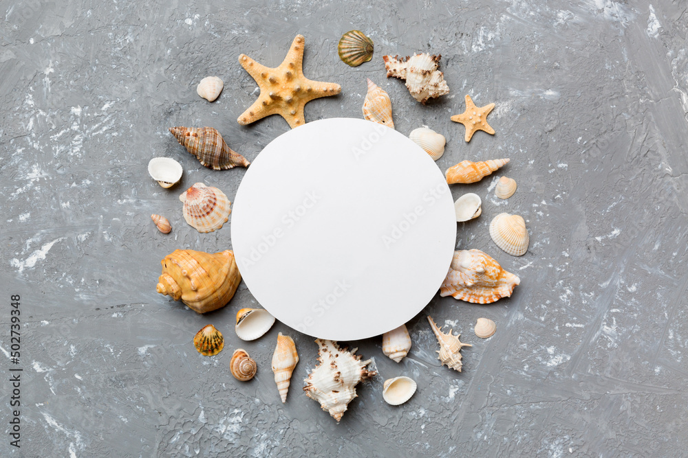 Summer time concept with blank greeting card and blank white paper on colored background. Seashells from ocean shore in the shape of frame separated with space for text top view Summer time concept with blank greeting card and blank white paper on colored background. Seashells from ocean shore in the shape of frame separated with space for text top view