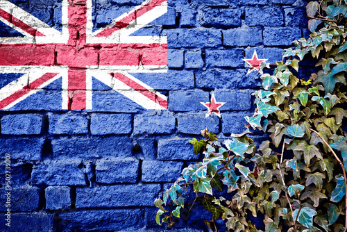 New Zeland grunge flag on brick wall with ivy plant © xbrchx
