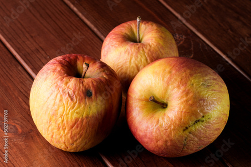 Foto Spoiled shriveled rotten apples on a dark wooden background close-up