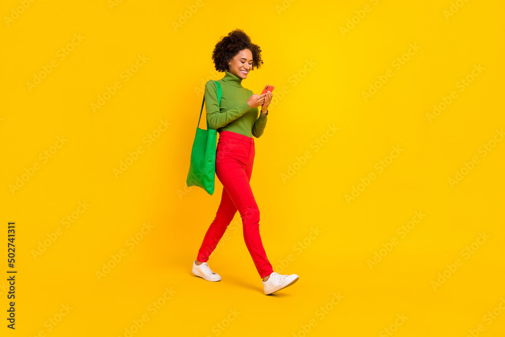 Full size profile side photo of young girl make shopping use mobile step empty space repost isolated over yellow color background