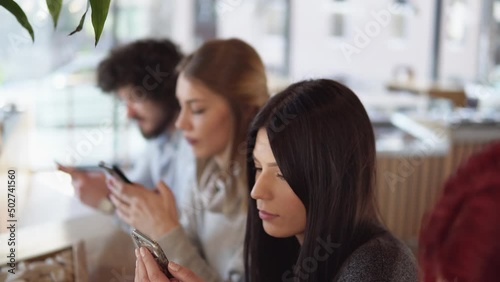 Friends using cell phones in a coffee shop, not talking to eachother and looking in the phone. Online life, internet and social media addiction photo