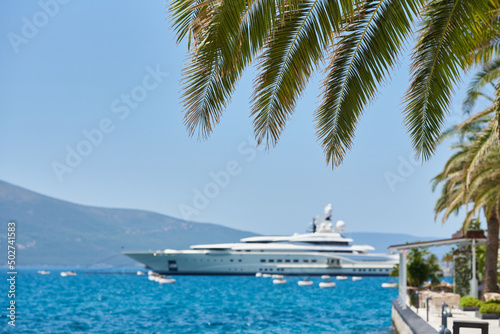 Palm leaves on the background of the sea and luxury yacht