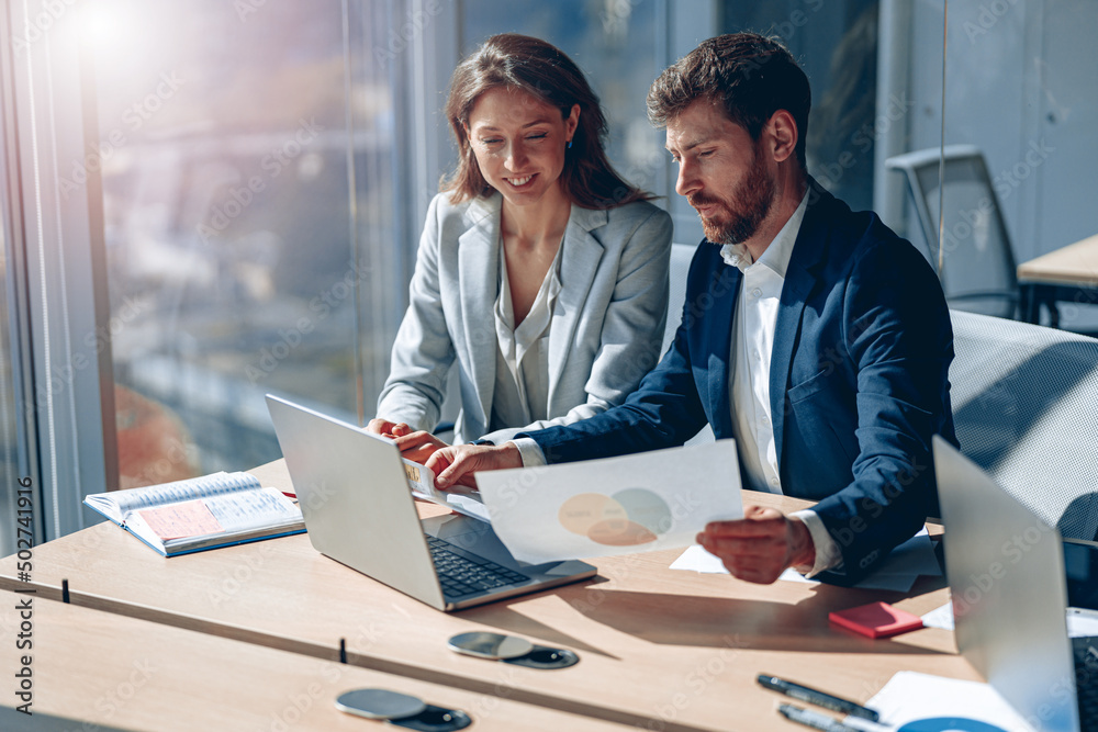 © Yaroslav Astakhov - Two business people during work meeting in modern office explaining statistics data to each other