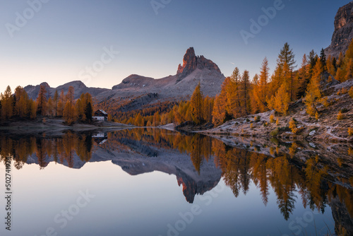 Fall sunrise on Lake Federa in the Italian Dolomites. Yellow larches create a unique atmosphere of this place.