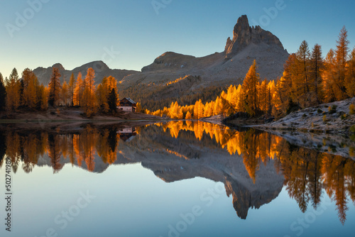 Fall sunrise on Lake Federa in the Italian Dolomites. Yellow larches create a unique atmosphere of this place.