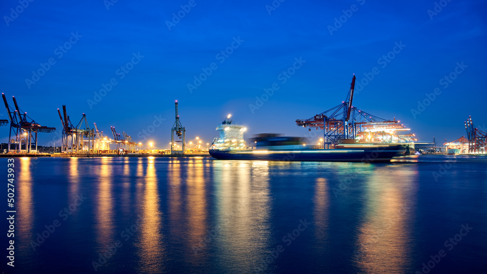 Cargo Vessel performing a turning maneuver at Terminal Burchardkai in City of Hamburg during night time on the river Elbe. Long exposure shot. Cargo Vessel performing a turning maneuver at Terminal Burchardkai in City of Hamburg during night time on the river Elbe. Long exposure shot.