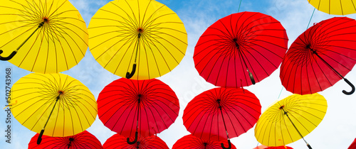 Red and yellow umbrellas hanging sky background bottom-up