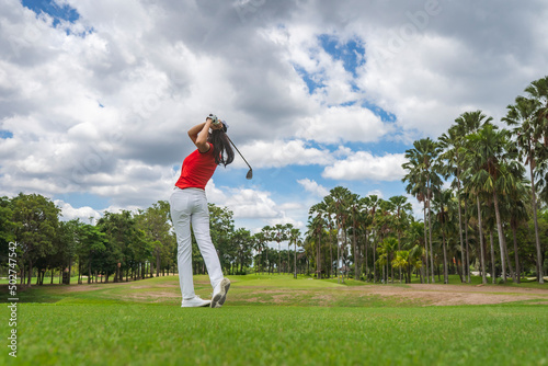 Female golf player playing golf in professional golf course.