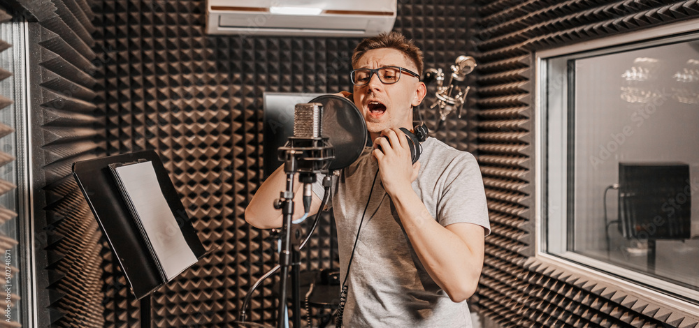 © Daria Lukoiko - The vocalist sings in the studio in a microphone. Man in headphones writes a podcast, an audiobook. Artist, recording an album, working with the label. Announcer records a speech at a radio station