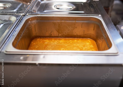 Spicy sauce for taco topping is kept warm in a double boiler at a market photo