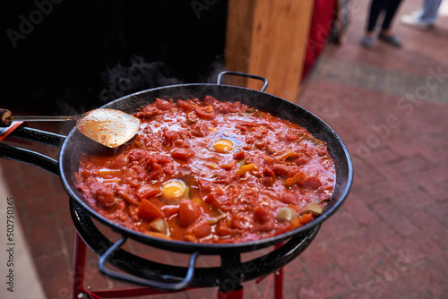 Fotografie A giant pan of shakshuka being cooked at a market outdoors